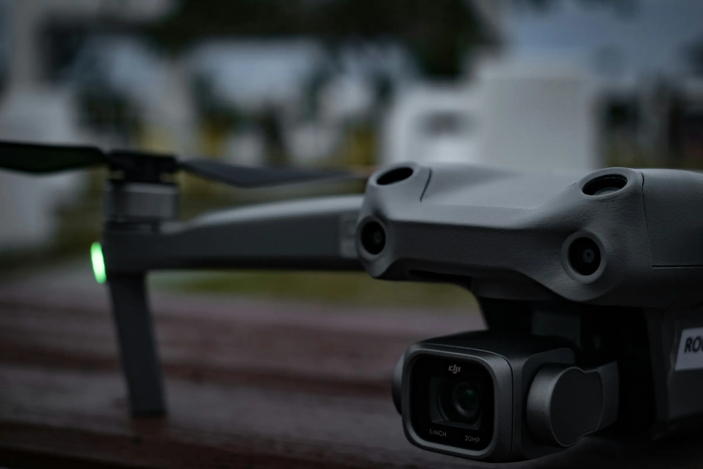 Camera drone powered up on a driveway at dusk, the pre-flight state before airspace authorization is confirmed