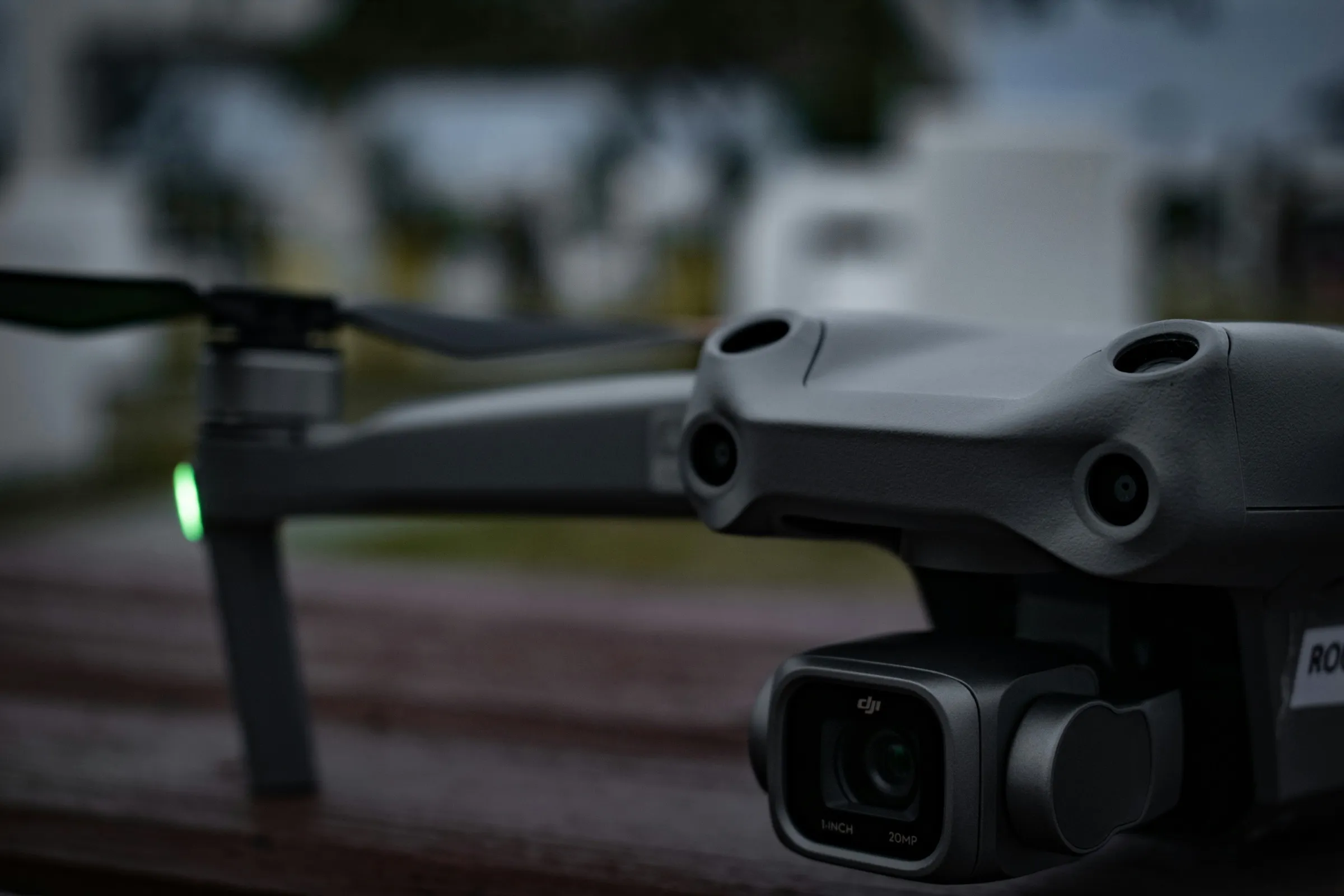Camera drone powered up on a driveway at dusk, the pre-flight state before airspace authorization is confirmed