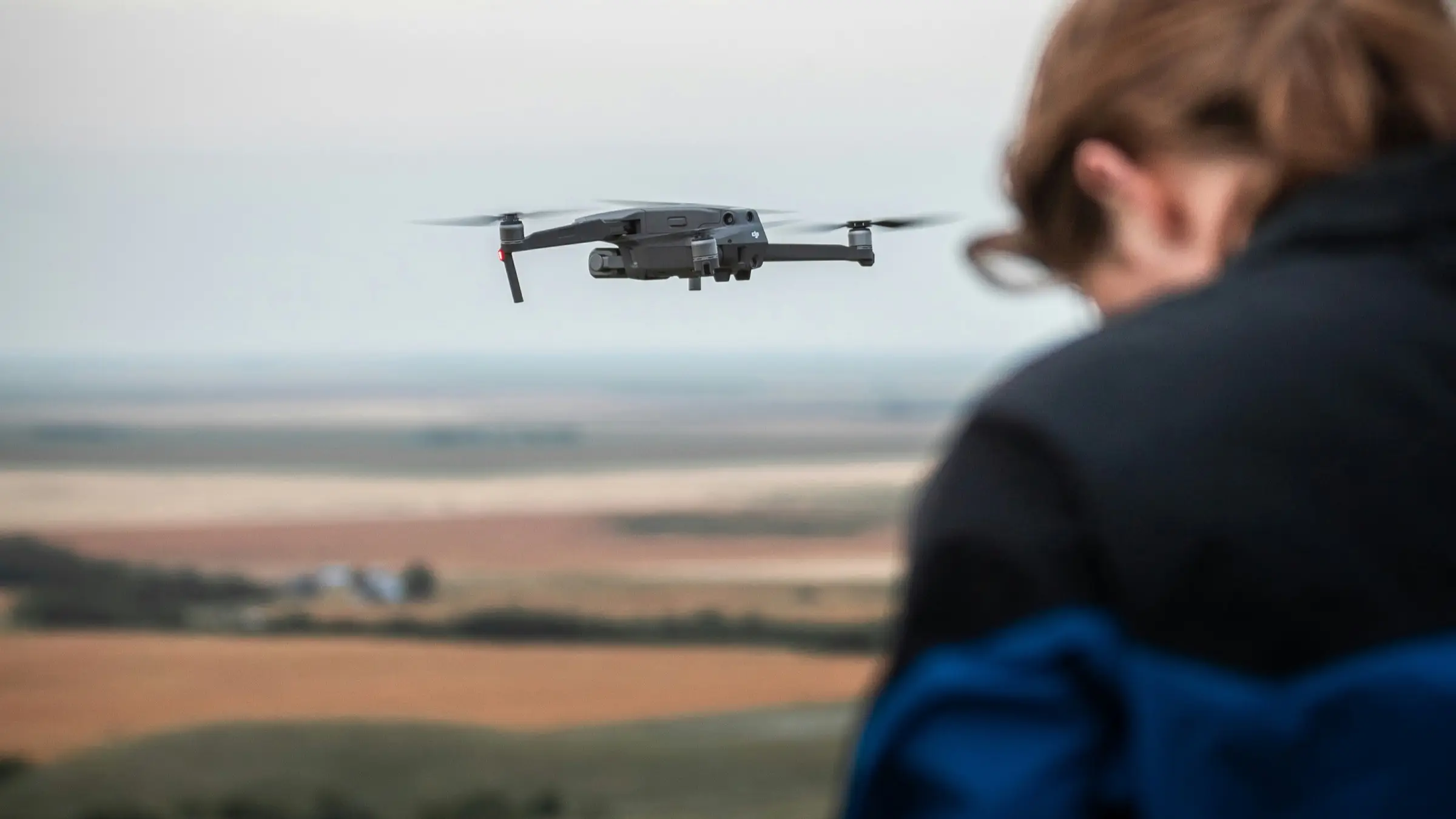 Pilot holding a camera drone in a hover during a shoot, the billable unit behind every rate on this page