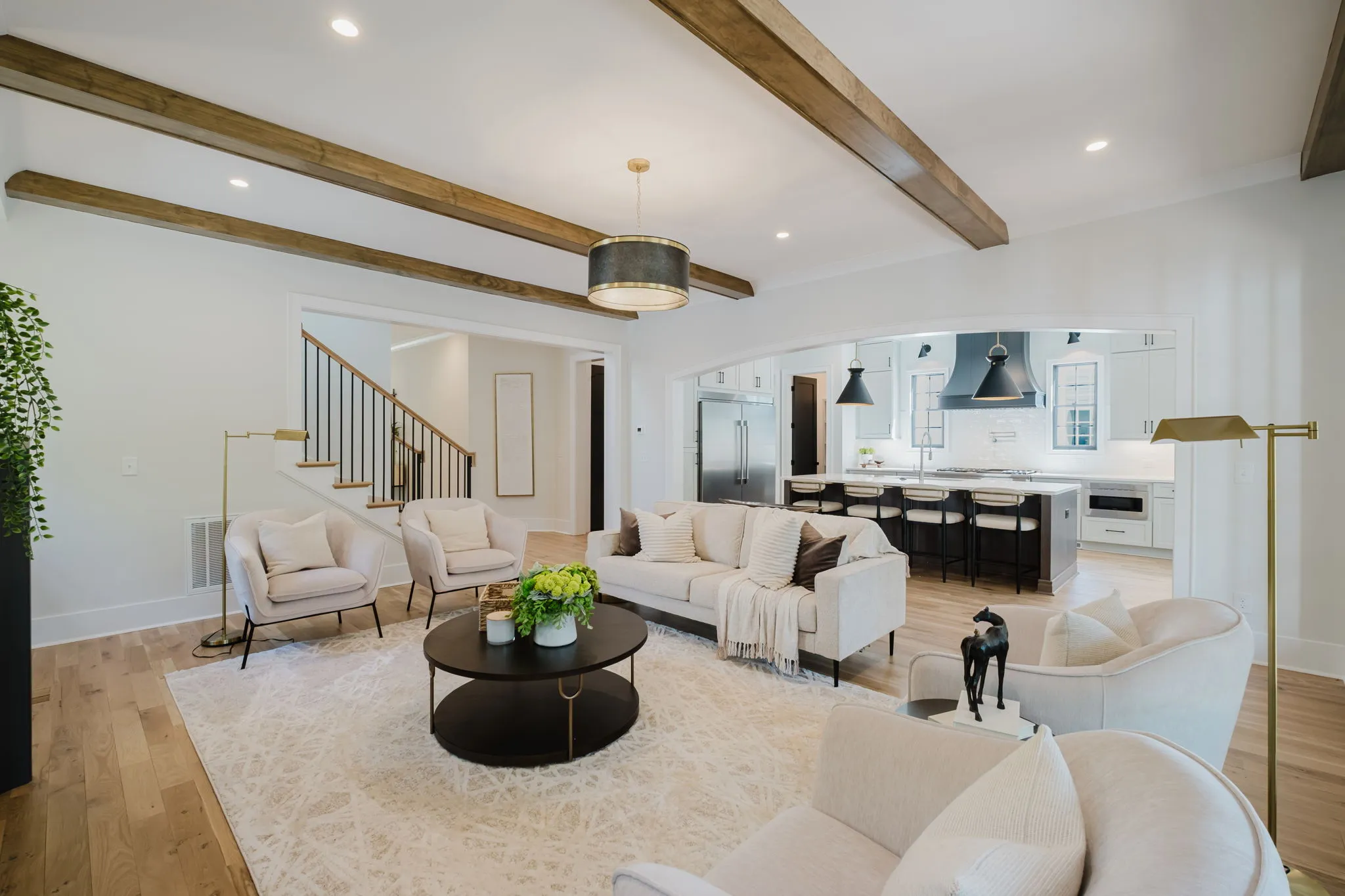 Open-concept living room with exposed beams opening through to the kitchen