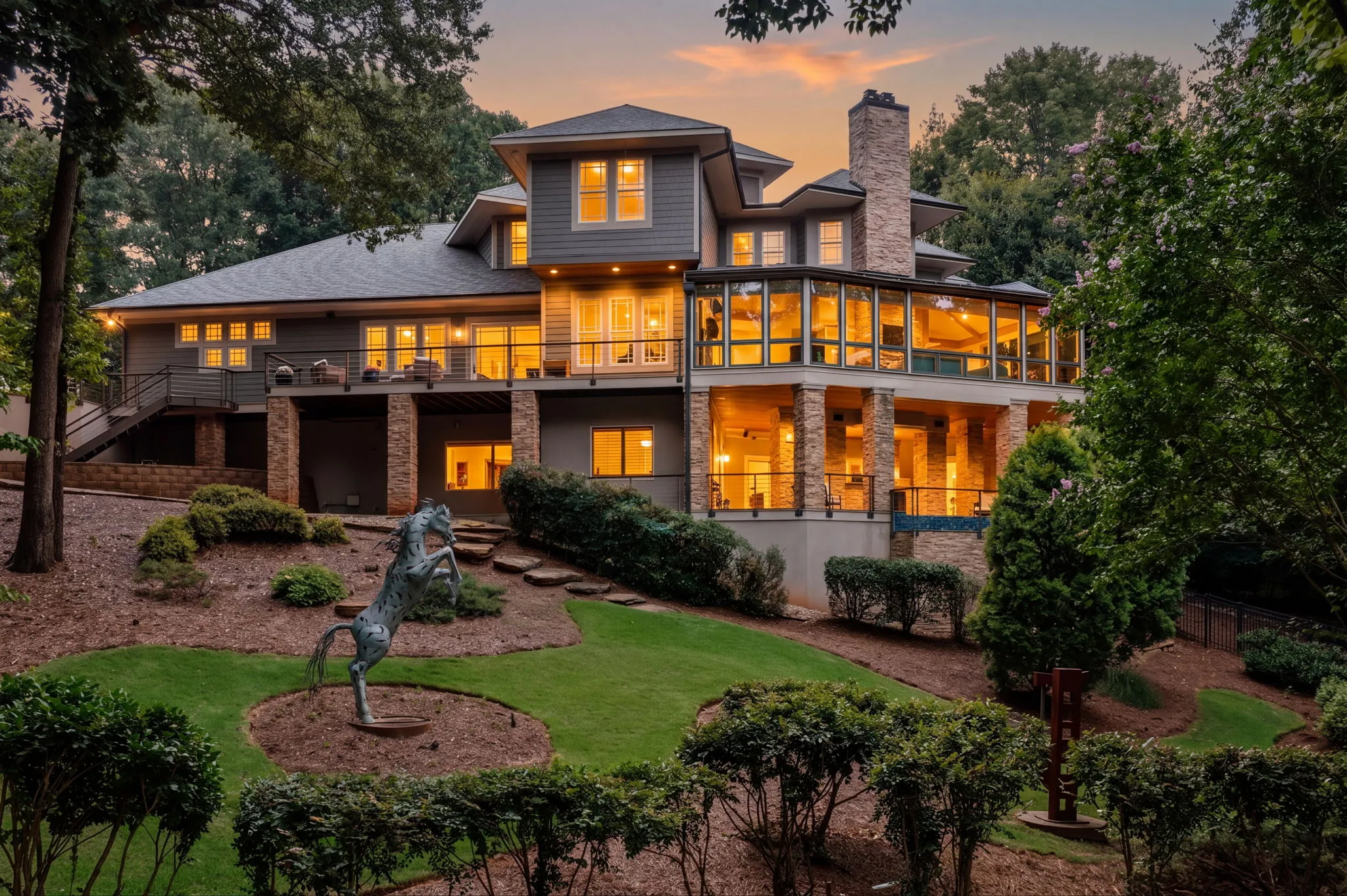 Multi-level estate at twilight with every window lit and the sunset behind it