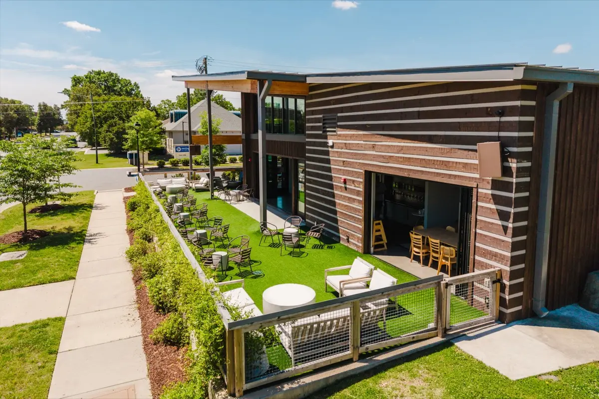 Aerial photo of Open Tap in south Charlotte showing the turf village green, outdoor seating, and the open garage door into the taproom